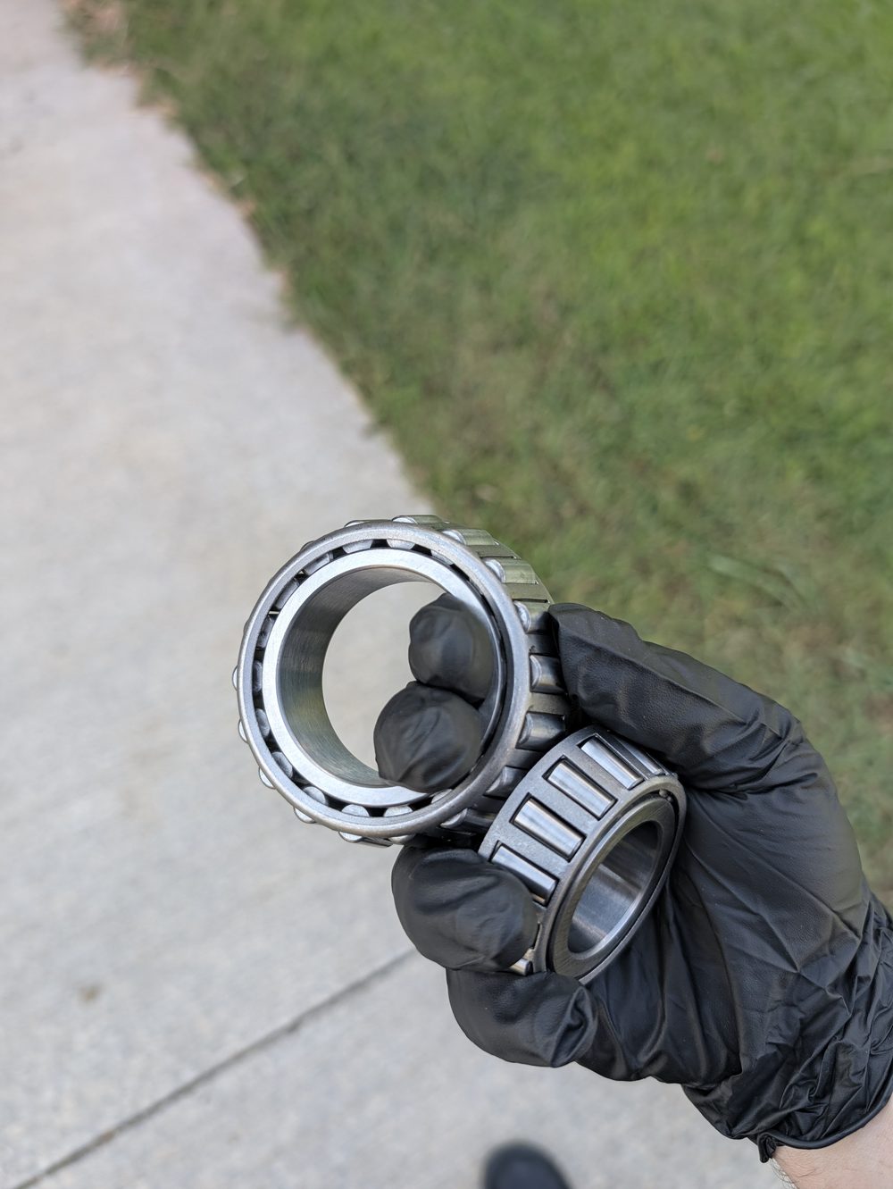 Worn trailer wheel bearings held up for inspection before replacement